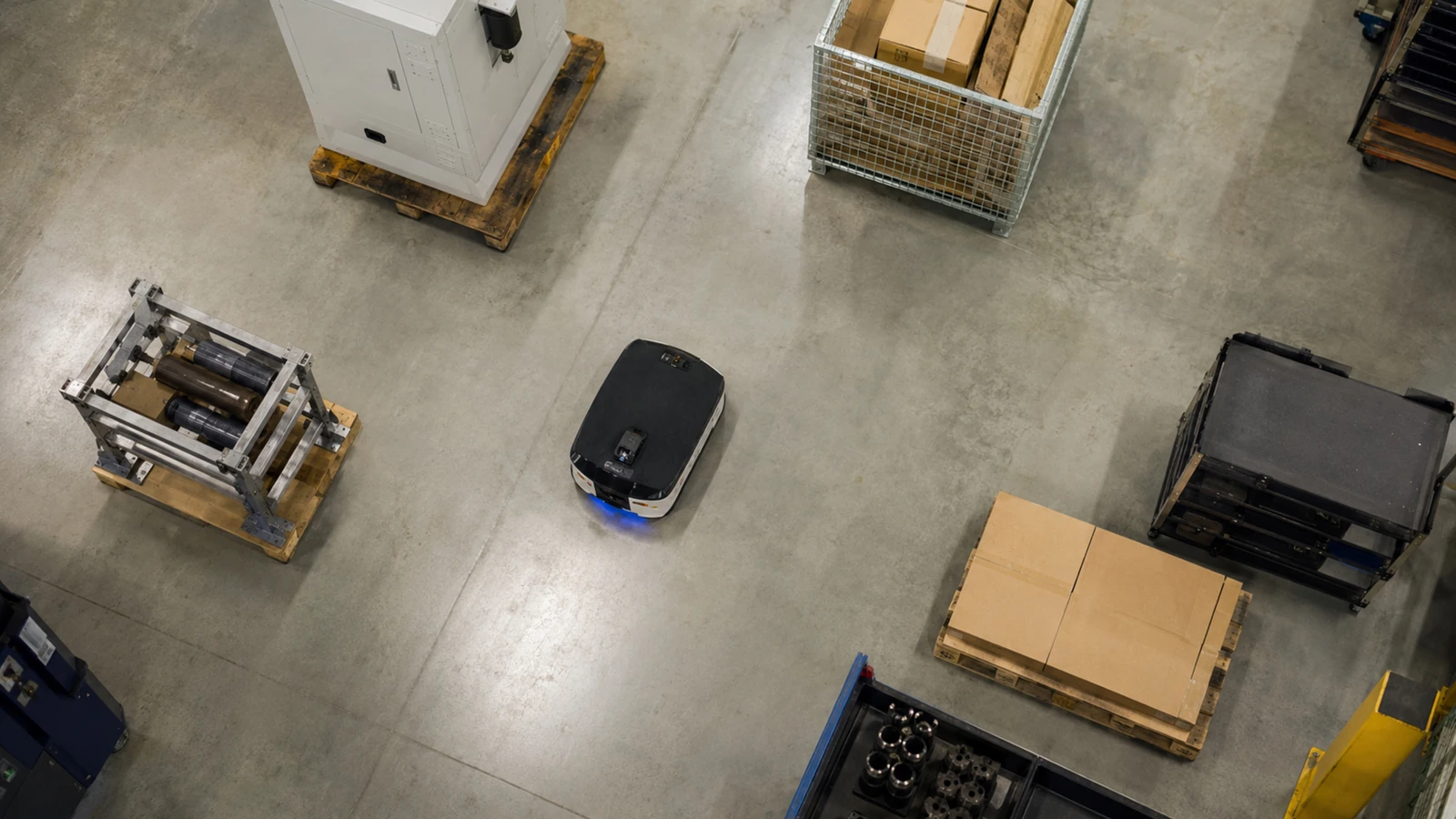 Aufsicht auf einen autonomen mobilen Roboter, der auf geschwungener Route mehrere Objekte umfährt