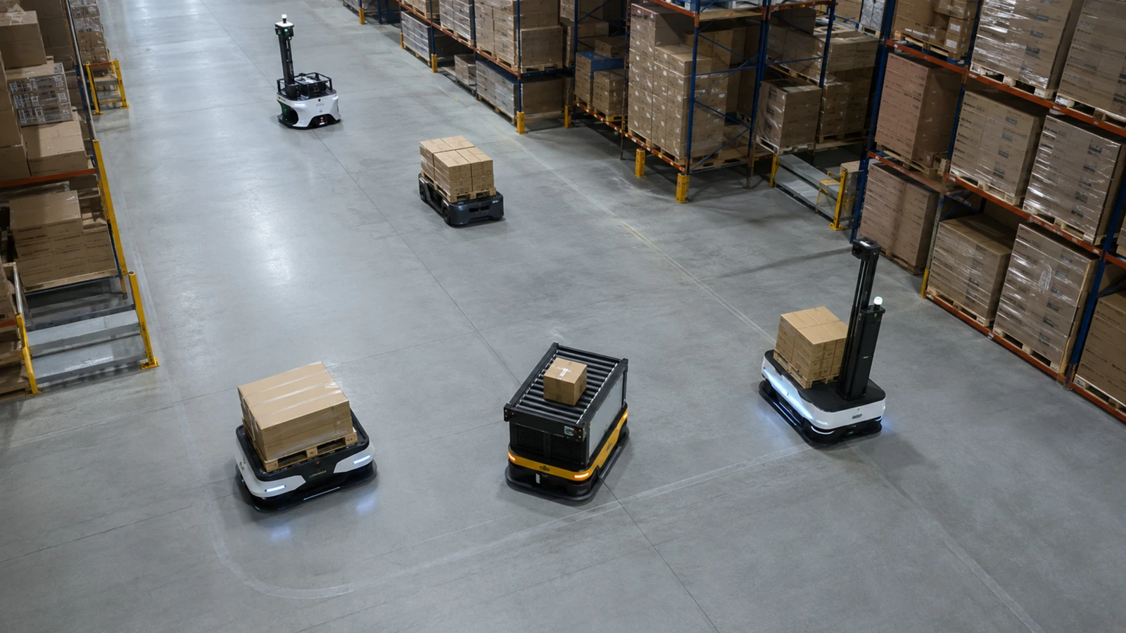 Aufsicht auf einen Lagergang, in dem sich die Wege mehrerer Robotertypen ordentlich kreuzen