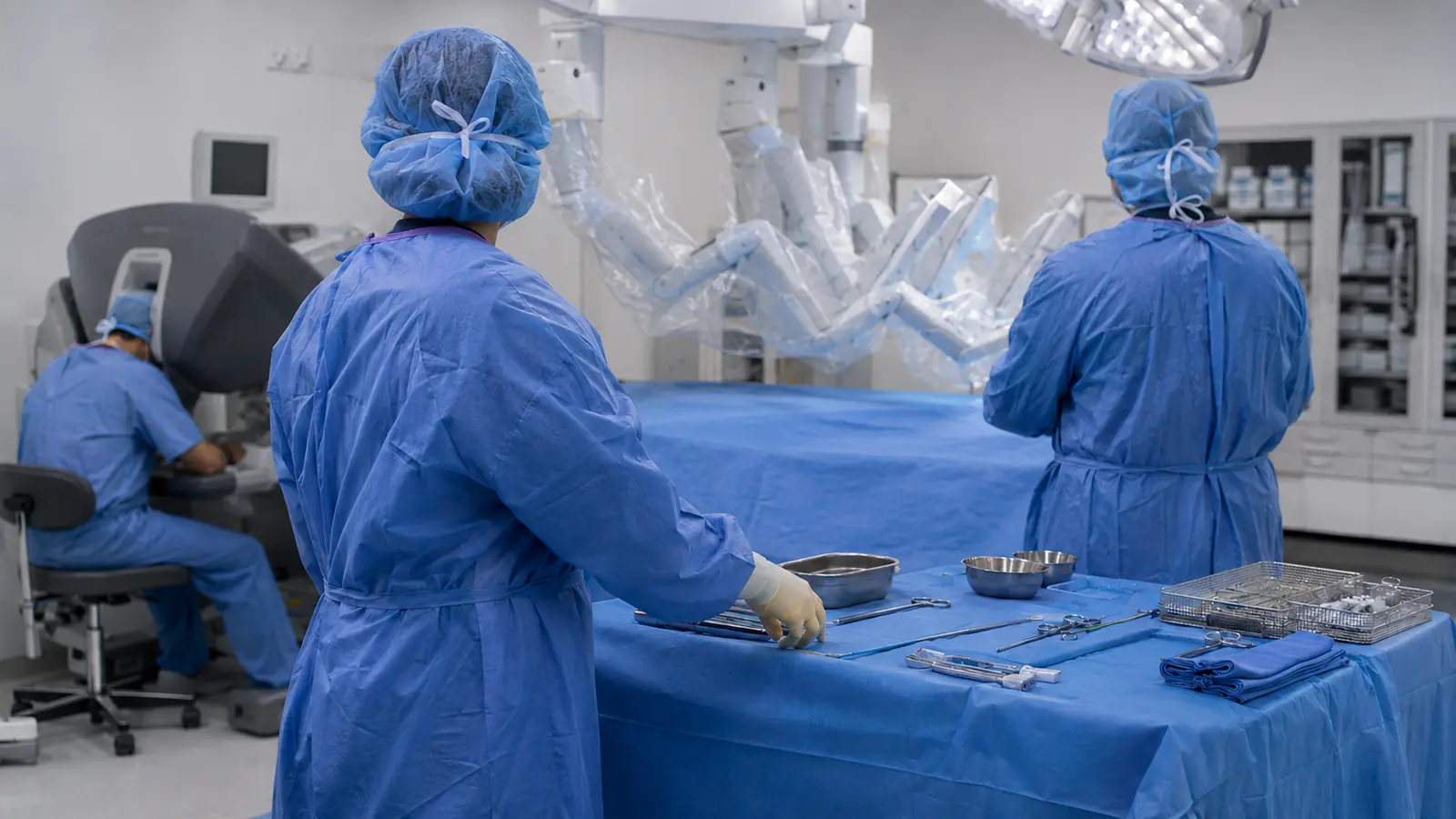 OP-Team im urologischen Saal assistiert am Tisch, der Operateur sitzt hinten an der Konsole